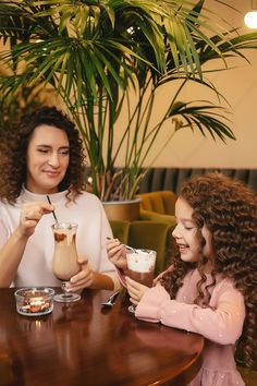 two women sitting at a table with drinks in their hands and one woman holding a drink