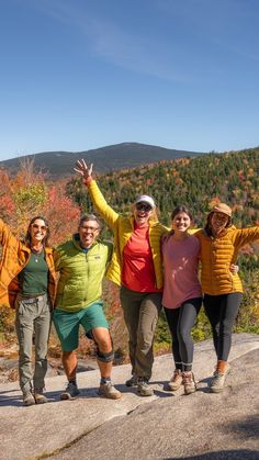 four people standing on top of a mountain posing for the camera with their arms in the air