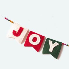 felt banner with the word joy hanging from it's side on a white background