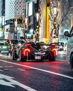 a car that is sitting in the street with its lights on and some cars behind it