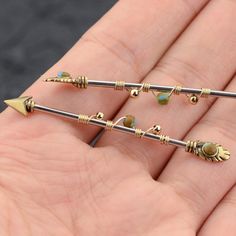 three small gold - plated arrows with green beads on them