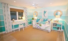 a bedroom decorated in blue and white with a bed, desk, mirror and window