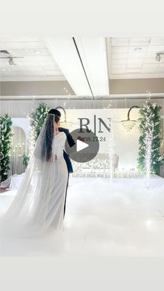 a bride and groom standing in front of a white backdrop