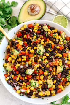 a white bowl filled with black beans, corn, avocado and cilantro