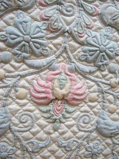 an embroidered quilt with pink and blue flowers on it's side, close up