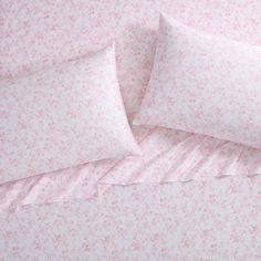 two pillows on top of each other with pink and white floral print in the background