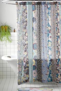 a bathroom with a shower curtain that has flowers on it and a rug in front of the shower