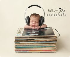 a baby with headphones is sleeping on top of a stack of books and cds