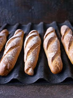 several loaves of bread sitting on top of a black tray next to each other