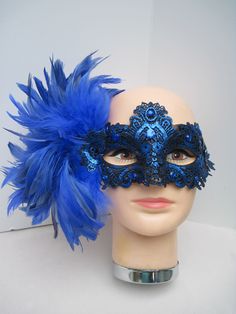 * Designed on a sturdy acrylic shiny half mask accented around the eyes with black liner and royal blue shiny embroidered flower and scrolled patterned lace in a custom design. * The right side is adorned with puffy plumes of fluffy and royal blue feathers. * To secure the mask there are two satin black ribbons on each side to be tied in the back. * A great piece for a Masked Ball, Class Reunion, Costume party or Play, Carnivale, Mardi Gras, Burlesque Occasion, Masquerade Ball, or Venetian Celeb Elegant Blue Eye Mask For Masquerade, Blue Venetian Mask For Carnival, Blue Venetian Masks For Carnival, Blue Venetian Masquerade Mask For Party, Blue Masks And Prosthetics For Carnival Party, Blue Masquerade Mask For Mardi Gras Costume Party, Blue Masquerade Mask For Mardi Gras Carnival, Blue Eye Mask For Carnival, Blue Party Eye Mask