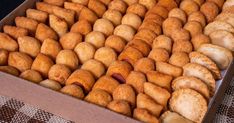 a box filled with lots of donuts on top of a checkered table cloth