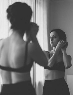 a woman is looking at her reflection in the mirror while wearing a bra and panties