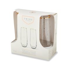 two wine glasses in a white box with gold dots on the bottom and one is empty