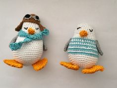 two small crocheted penguin dolls sitting next to each other on a white surface