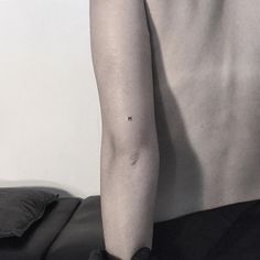 a person with a small tattoo on their left arm and the other arm behind them