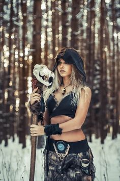 a woman dressed in native american clothing holding a bear skull and wearing a headdress