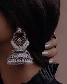 a close up of a woman's ear wearing earrings with pearls and beads on it