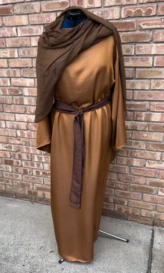 a brown robe is on display in front of a brick wall