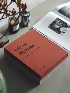 an open book sitting on top of a table next to a vase with flowers in it