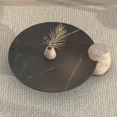 a black table with two vases and a palm leaf on top, sitting on a carpeted floor