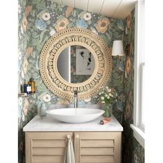 a bathroom with a sink, mirror and wallpapered walls in the background that has flowers on it