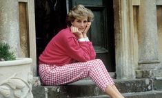 a woman sitting on the steps in front of a building talking on her cell phone