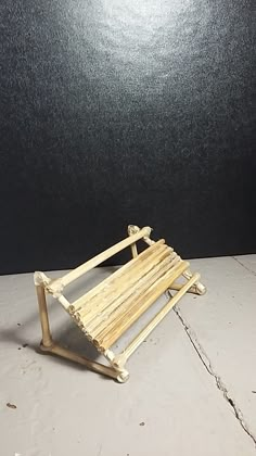 a small wooden bench sitting on top of a white tile floor next to a black wall