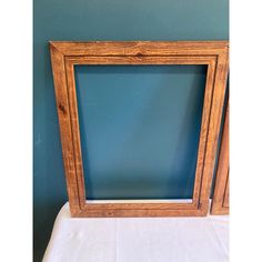 a wooden frame sitting on top of a white cloth covered table next to a blue wall