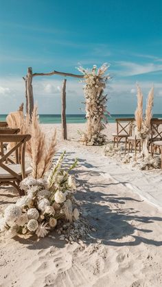 an outdoor ceremony set up on the beach with chairs and flowers in front of it