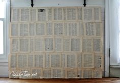 an old book is hanging on the wall in front of a window that has been made out of books