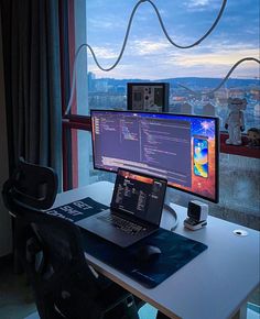 a laptop computer sitting on top of a desk in front of a monitor and keyboard