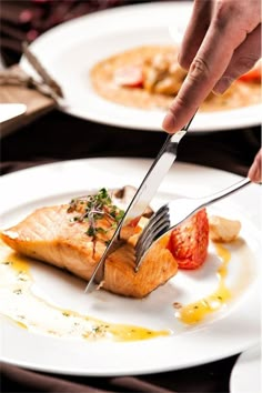 a person is cutting up some food on a plate with a knife and fork in it