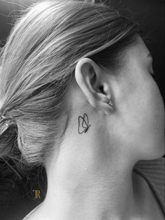 a woman's neck with a small flower tattoo on her left side behind the ear