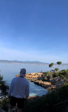 a man standing on top of a cliff next to the ocean