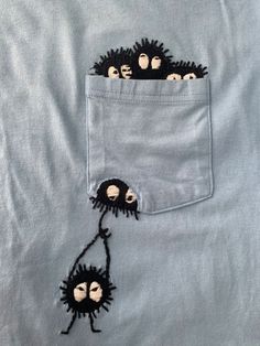 two small black monkeys sticking out of the pocket of a light blue shirt