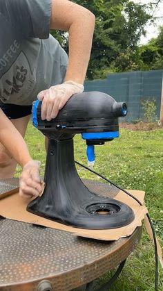 a woman is sanding the top of a table with an electric hand held sander