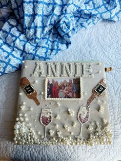 an old photo frame with some beads and pearls on it, sitting on a bed