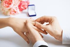 two people holding hands and touching each other's fingers with a cell phone in the background