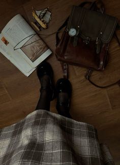 a woman is sitting on the floor with her feet propped up next to a book and purse