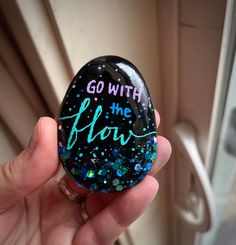 "Motivational Painted rock, inspirational rocks, Glitter Gift, Kindness Rock Gift, Painted Stones, One of a kind. Hand painted on a flat beach pebble with colorful acrylic paint, saying: \"Go with the Flow.\" Holographic glitter along the edges that changes color depending on viewing angle. Sealed with a coat of glossy resin. The bottom of rock has small artist initials. These make unique gifts for loved ones or yourself. Size: about 2.5 inches tall, 2 inches wide You will get the rock pictured, Painted Rocks Affirmations, Metallic Painted Rocks, Unique Painted Rocks, Painted Rocks Ideas Easy, Kindness Rock Garden, Kindness Rocks Ideas, Happy Rock