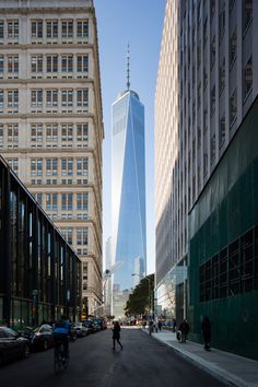 people are walking down the street in front of tall buildings and one world trade center