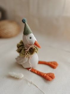 a small white bird with a green hat on it's head sitting on a bed