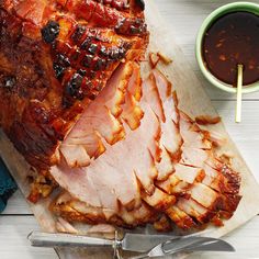 sliced ham sitting on top of a cutting board next to sauces and utensils