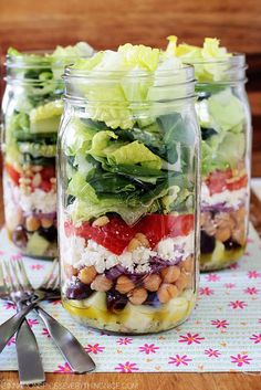 three mason jars filled with salads on top of a table