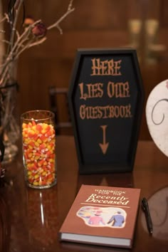 there is a halloween decoration on the table next to a glass with candy in it