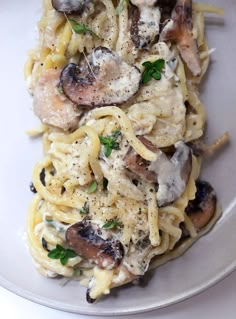 a white plate topped with pasta covered in mushrooms