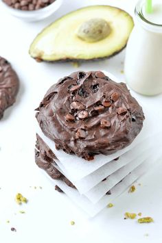 a chocolate cookie sitting on top of napkins next to an avocado