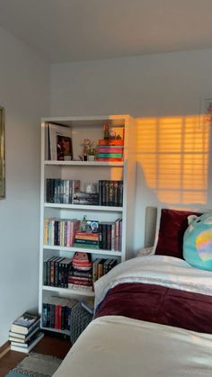 a bedroom with a bed, bookshelf and other items on the shelves in front of it