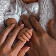 two hands are holding a baby's hand while it is wrapped in a blanket