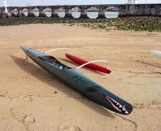 a kayak is laying on the sand with a red paddle in front of it